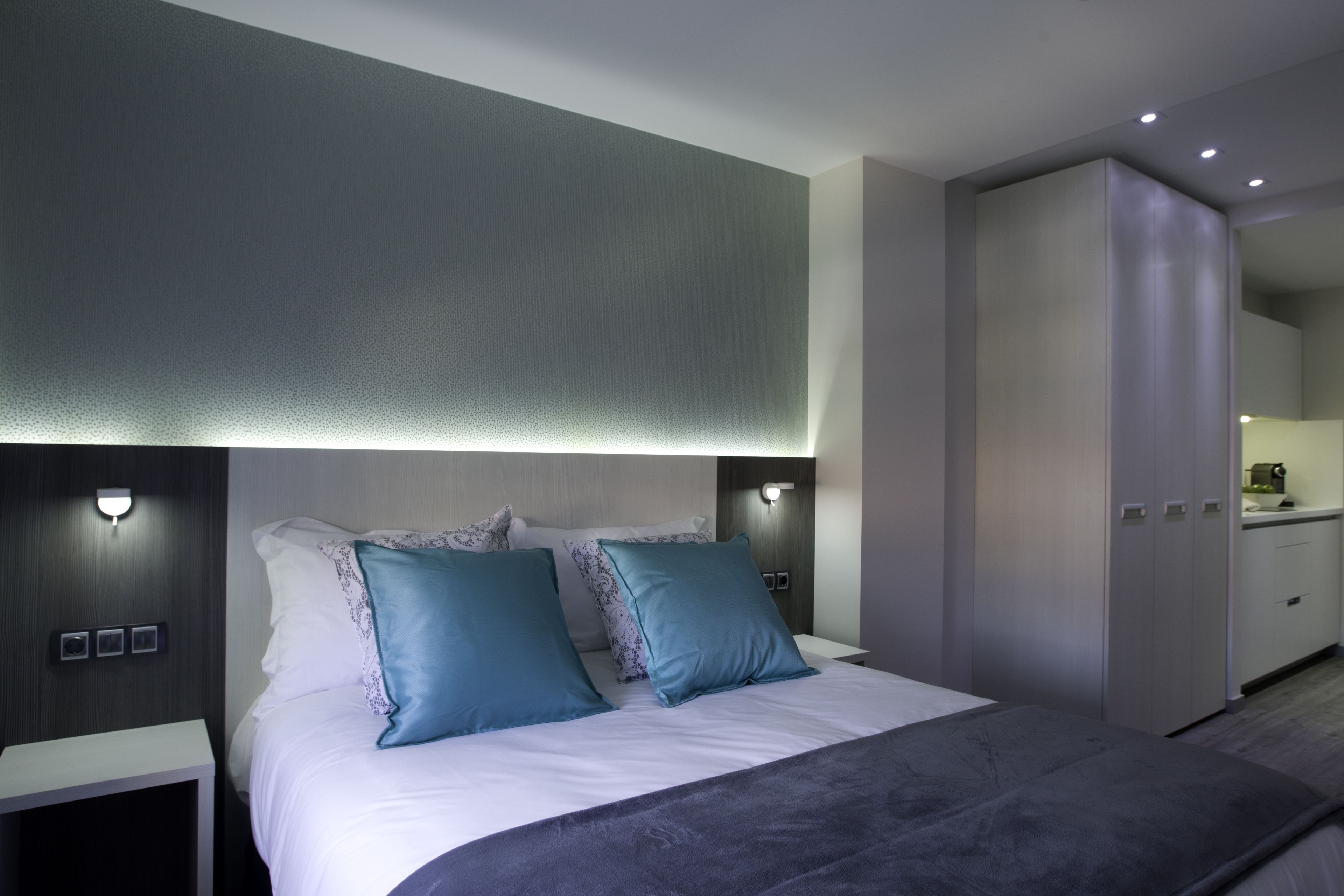 A modern bedroom with a large bed, two side tables, and a wardrobe.