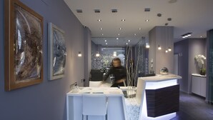Een moderne receptiebalie met witte barkrukken en lijstwerken aan de muur.