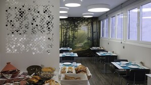 Een ontbijtbuffet met diverse gerechten en een wanddecoratie van een bos.