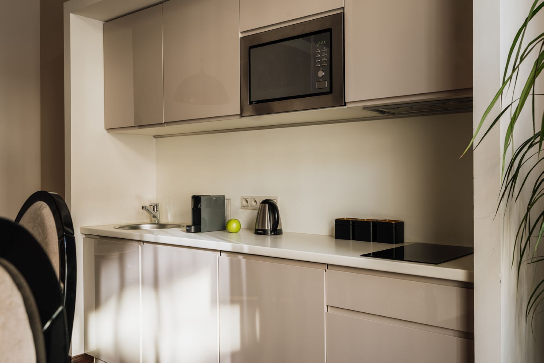 Een moderne keuken met een magnetron, koffiezetapparaat en waterkoker op het aanrecht.