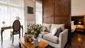 A cozy living room with a wooden panel wall, a sofa, a coffee table with a vase of flowers, a desk with a chair, and a globe. - Topolowa Residence by StayLab (Kraków)