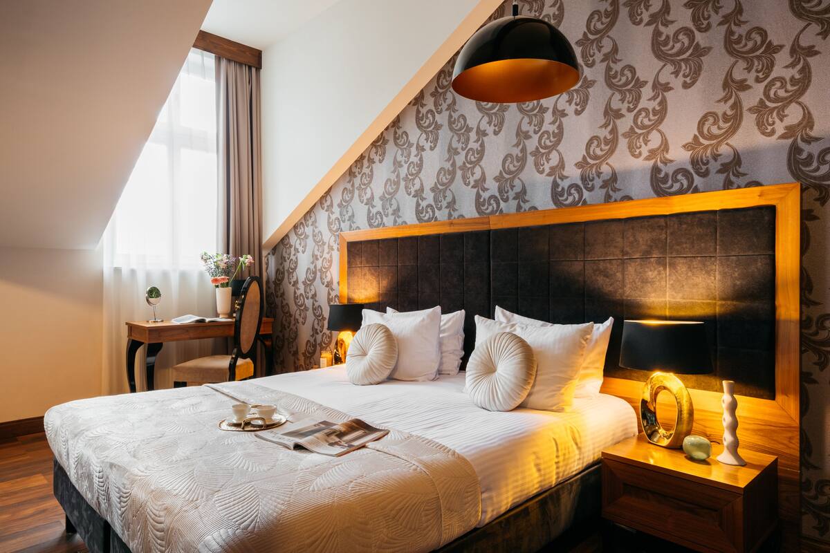 A hotel room with a large bed, a wooden nightstand, a desk, and a chair.