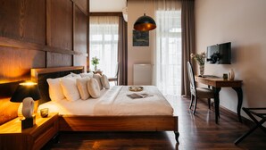 A well-lit bedroom with a wooden bed, bedside table, and a desk with a chair. - Topolowa Residence by StayLab (Kraków)