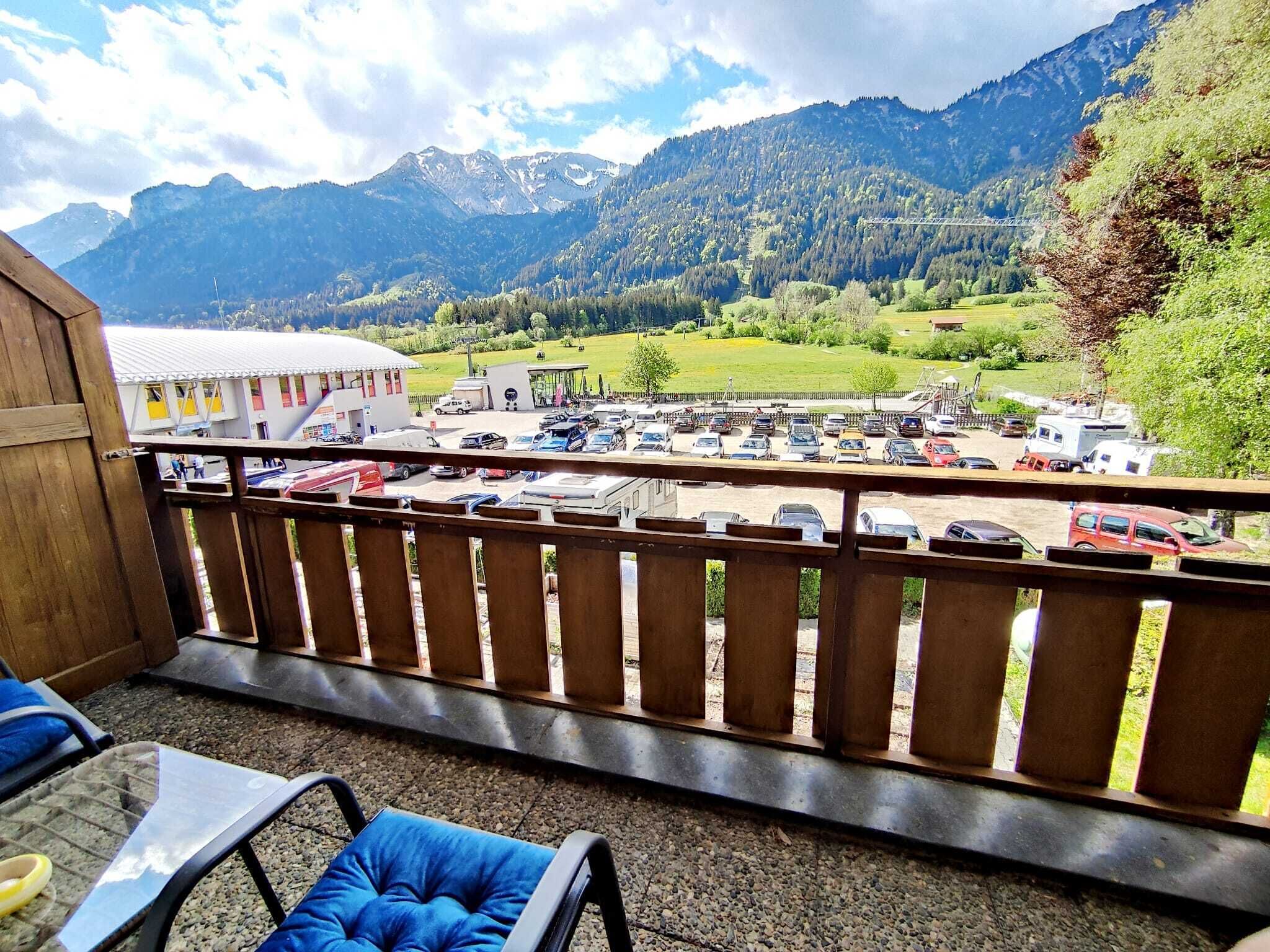 A balcony with a view of a parking lot and mountains.