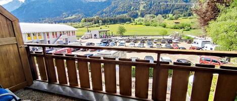 A balcony with a view of a parking lot and mountains.