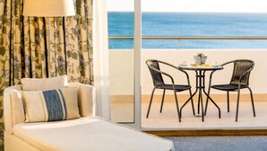 Una habitación de hotel con cama, una mesa y sillas, y vista al océano.