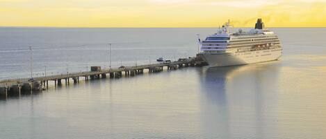 A large cruise ship docked at a pier with calm waters and a clear sky.