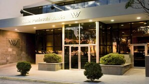Exterior del Hotel Peninsula Valdés con un diseño moderno, que incluye un acceso de vidrio y un logotipo en la fachada.