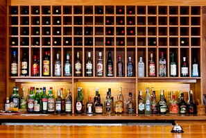 Um bar com uma estante de madeira para vinhos e diversos frascos de bebidas alcoólicas.