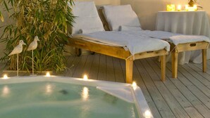 Un área de spa con un banco de madera, un jacuzzi y una mesa con velas.