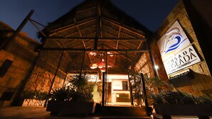 A hotel entrance with a thatched roof, a reception desk, and a sign reading "Ousada ENSEDA 2000 GOURNINGS". - Pousada Enseada dos Golfinhos (Tibau do Sul)