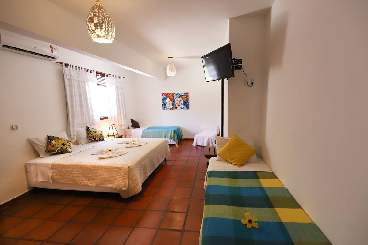 Ein Hotelzimmer mit zwei Betten, einem Flachbildfernseher, einer Deckenleuchte und einem Bild an der Wand.