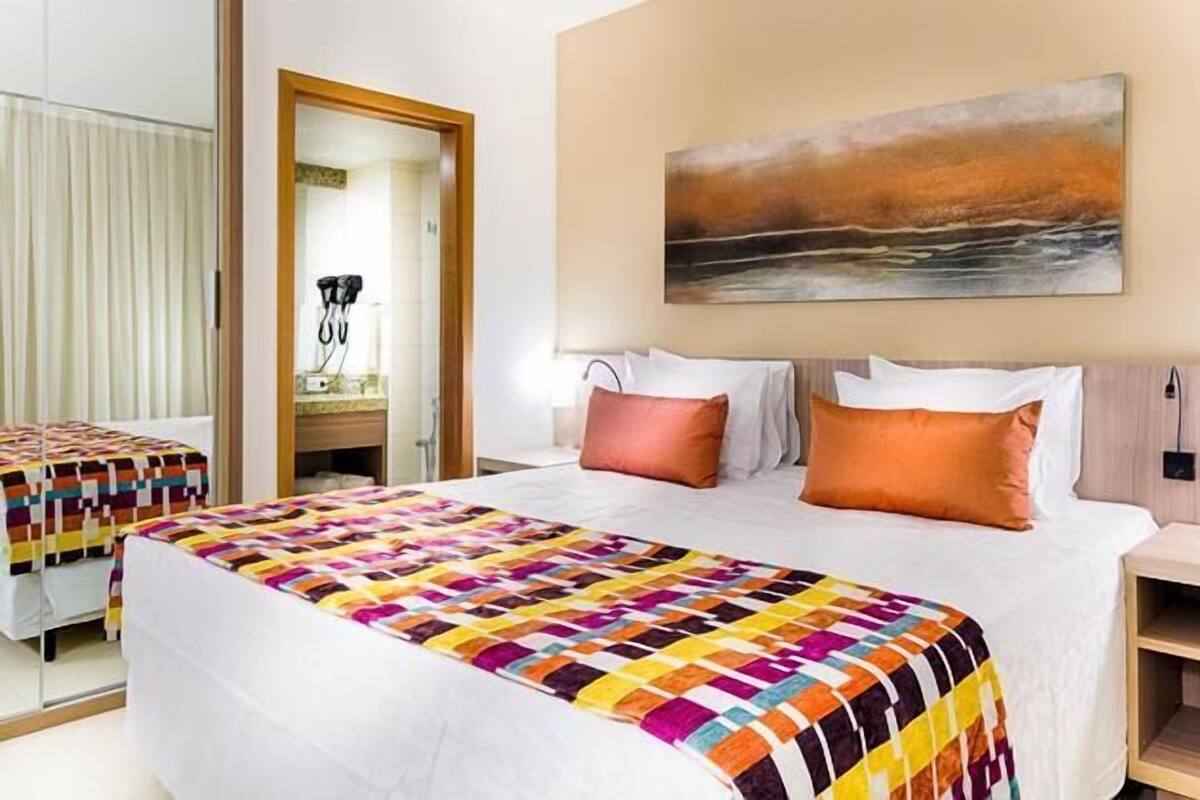 Ein Hotelzimmer mit zwei Betten, einem großen Sonnenuntergangsbild und einem hölzernen Nachttisch.