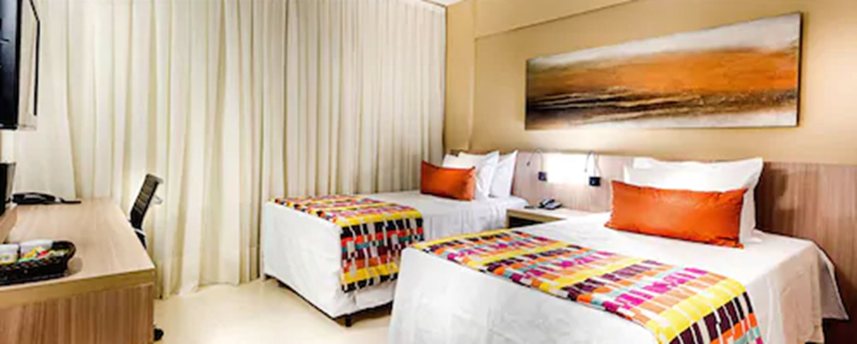A hotel room with two beds, a desk, and a large painting on the wall.