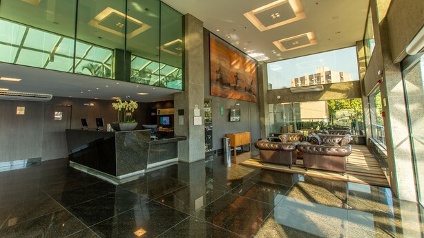 Eine moderne Lobby mit einer Rezeption, einer Sitzecke und großen Fenstern mit Blick ins Freie.