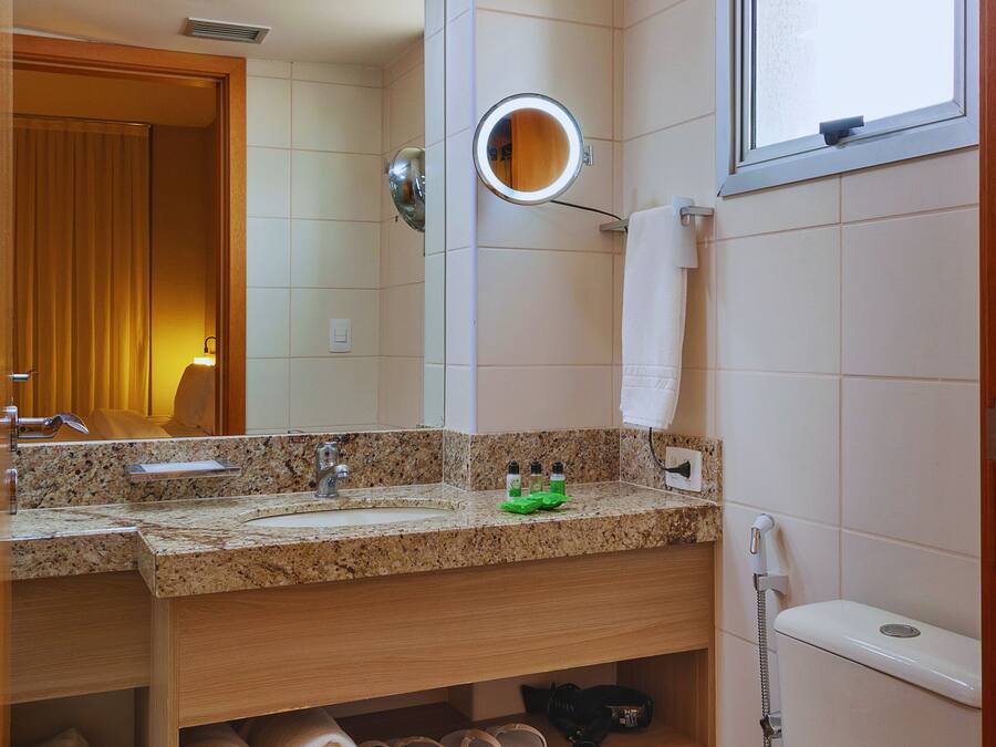 A bathroom with a sink, mirror, towel rack, and toilet.