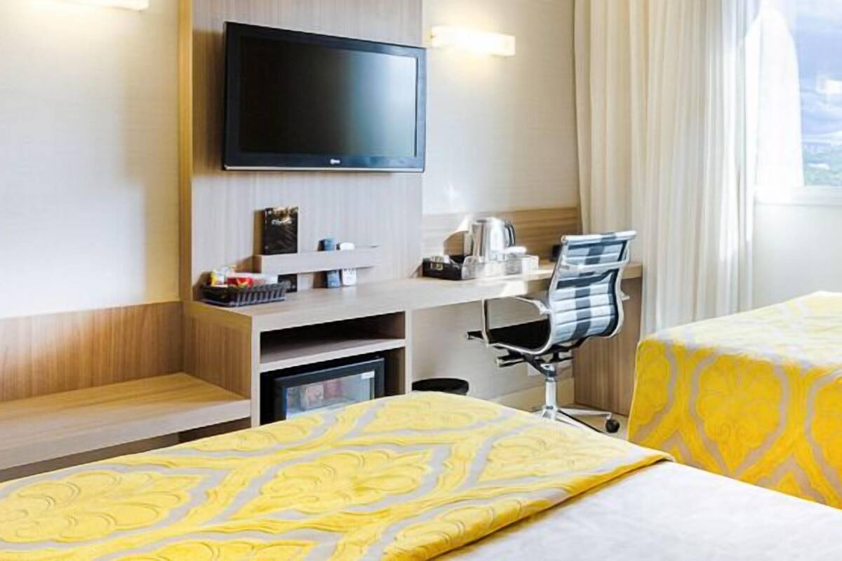Une chambre d’hôtel avec deux lits, un bureau, une télévision et une fenêtre donnant sur la ville.