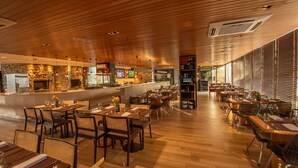 Ein geräumiges Restaurant mit Holzboden und hoher Decke. Tische sind zum Essen bereitgestellt, und im Hintergrund ist eine Küche erkennbar.