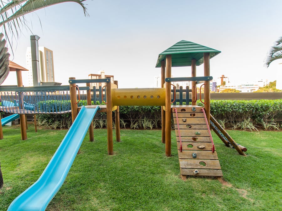 A playground with a blue slide, climbing net, and wooden climbing structures.