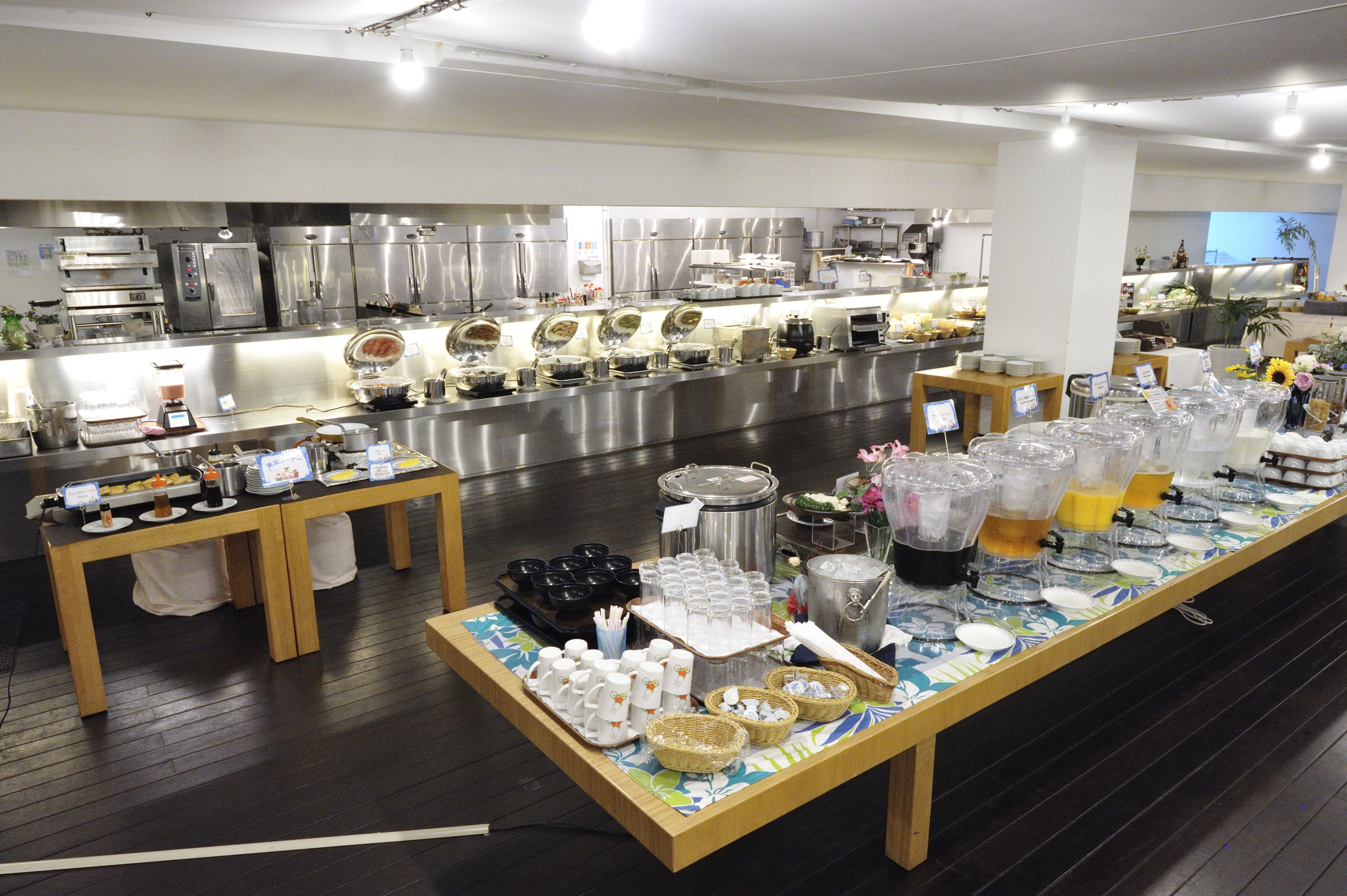 A buffet setup with various food and drink stations, including trays, bowls, and beverage dispensers.