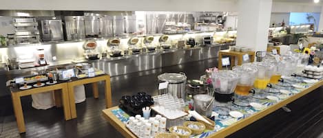 A buffet setup with various food and drink stations, including trays, bowls, and beverage dispensers.