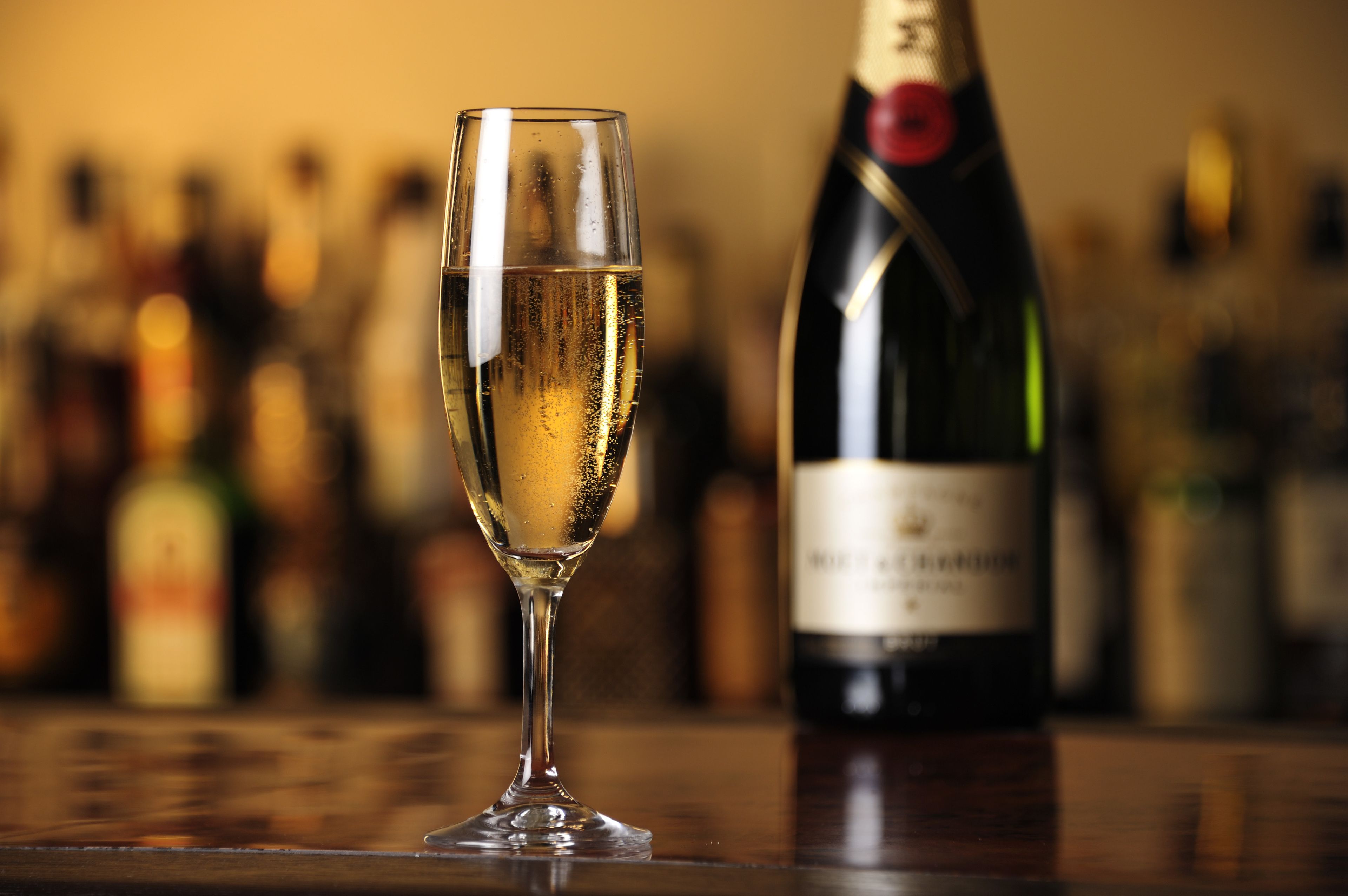 A glass of champagne and a bottle of wine on a wooden table.