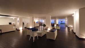 Eine geräumige Lobby mit einer Rezeption, gemütlichen Sitzgelegenheiten und Blick auf den Ozean.