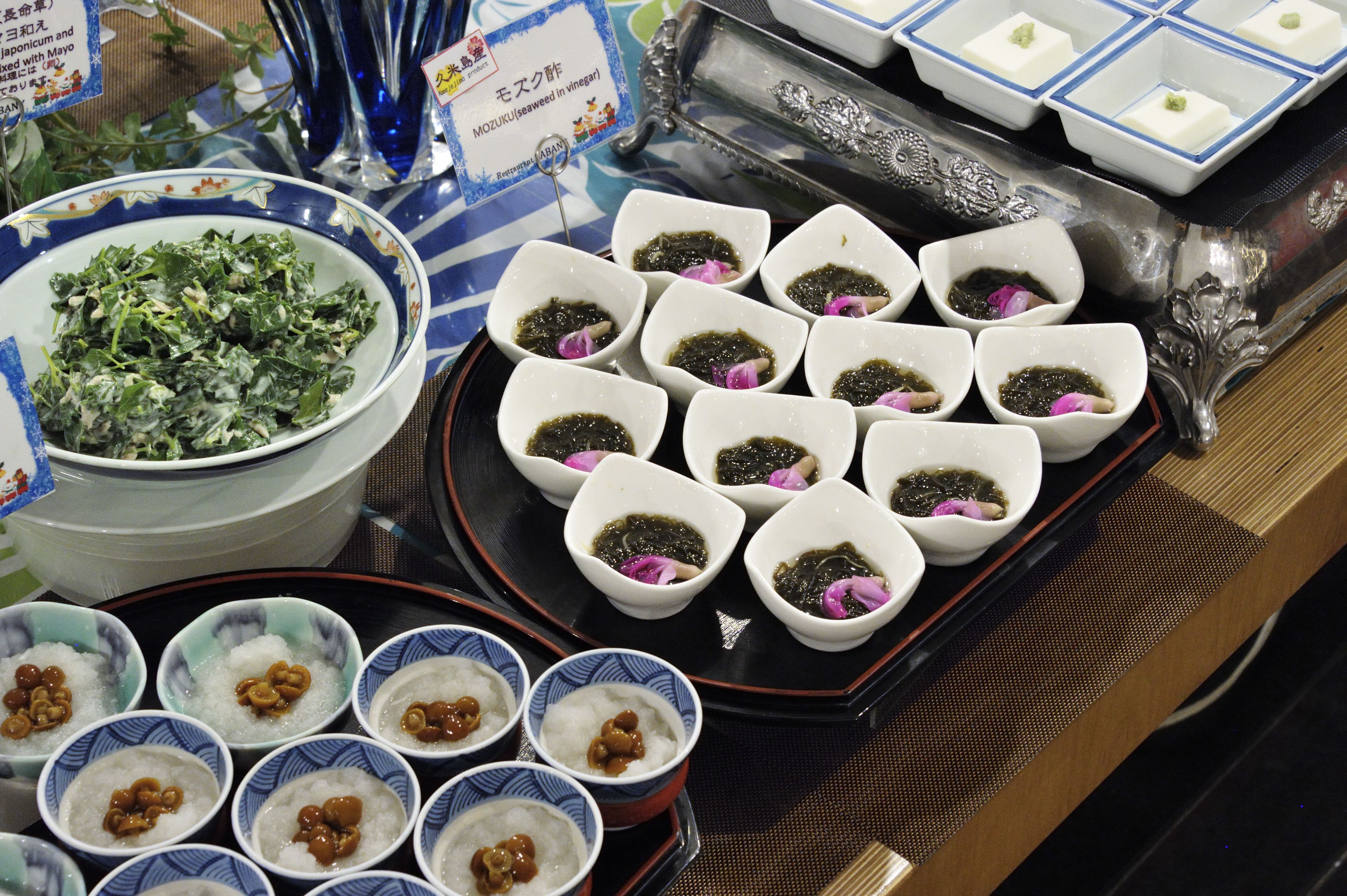A variety of Japanese dishes including seaweed, rice, and a bowl of greens.