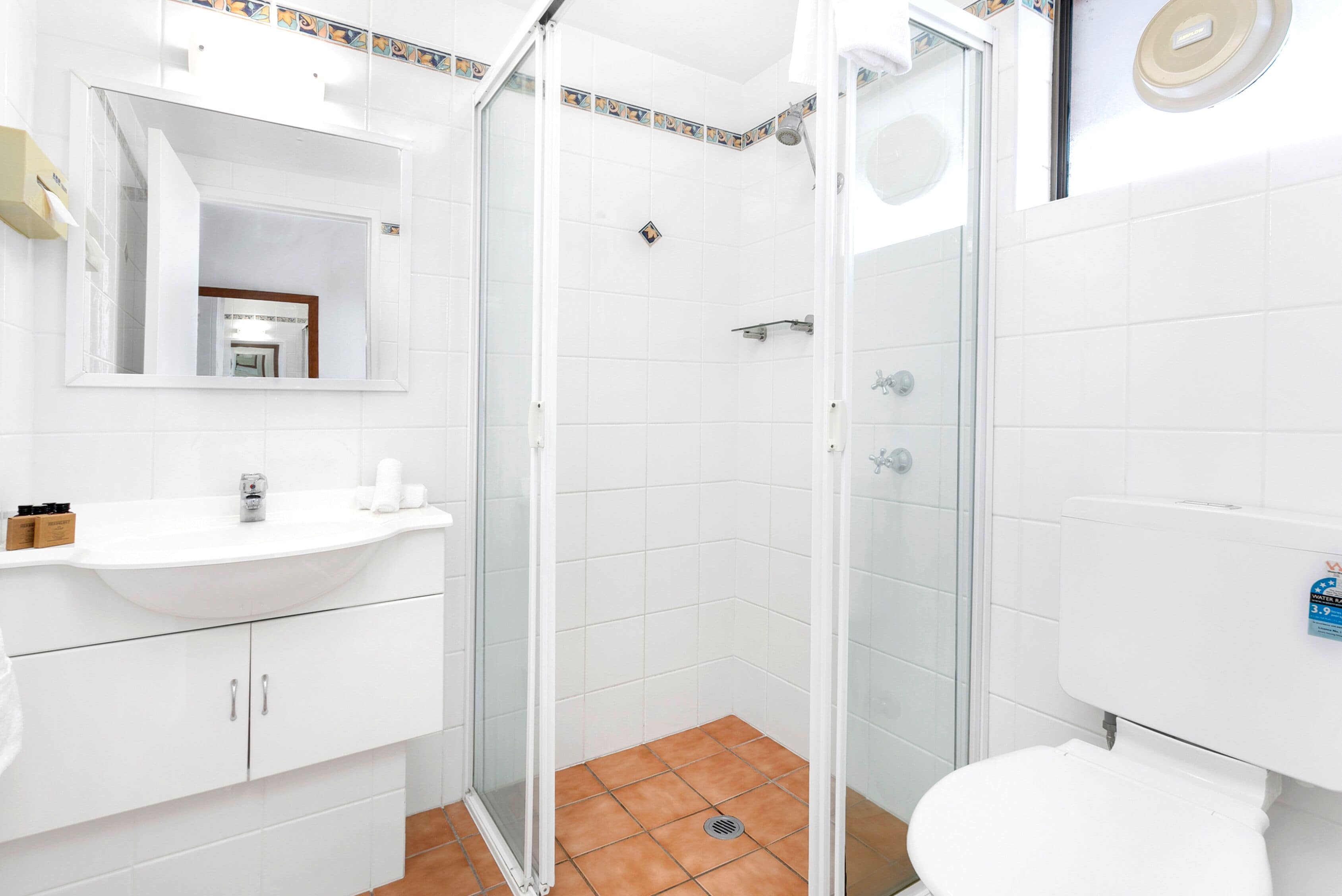 Un baño con lavamanos, espejo y retrete blancos.
