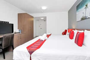 Habitación de hotel con cama, escritorio, televisor y un cuadro en la pared.