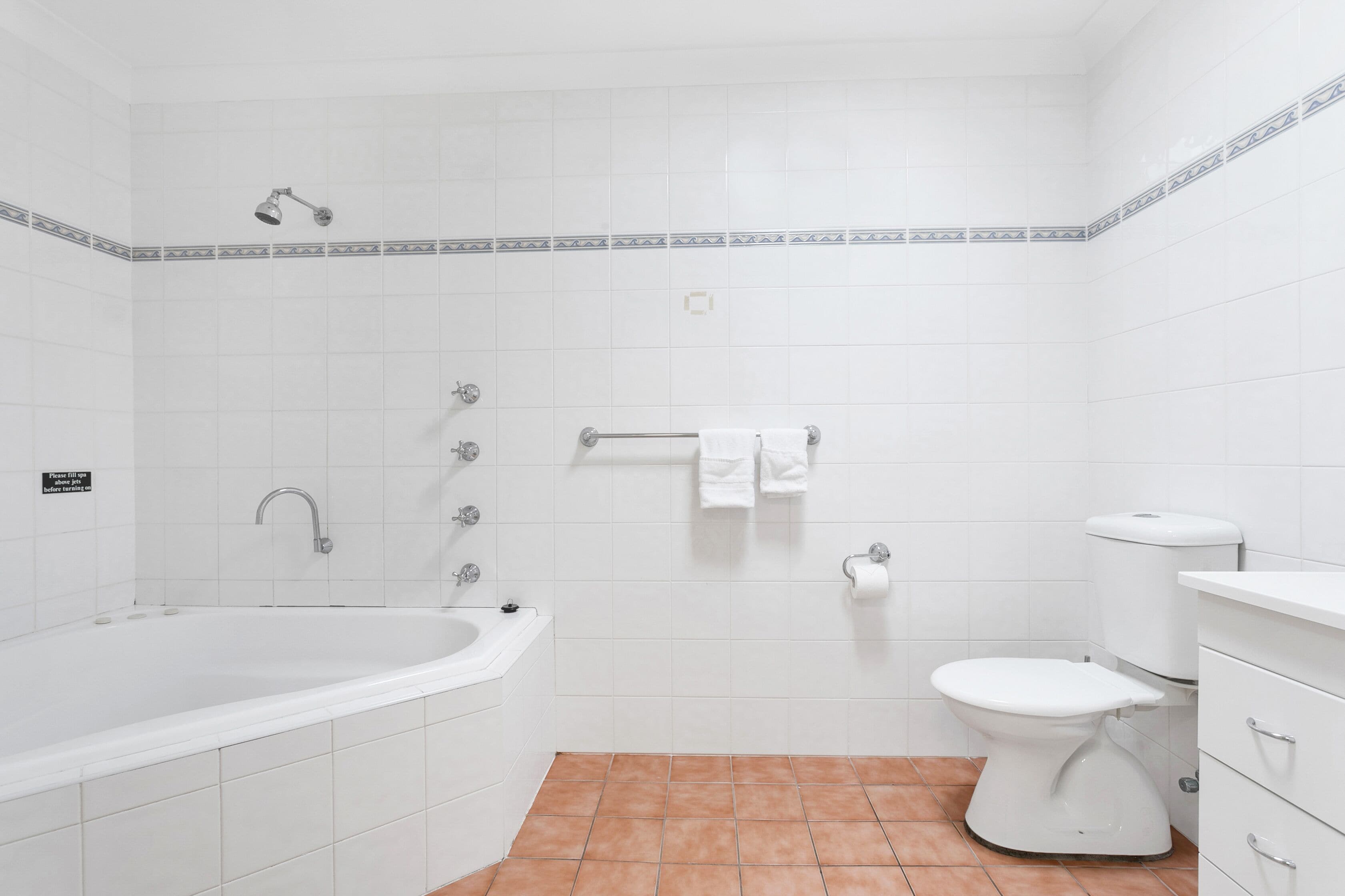 A bathroom with a bathtub, toilet, and a towel rack.
