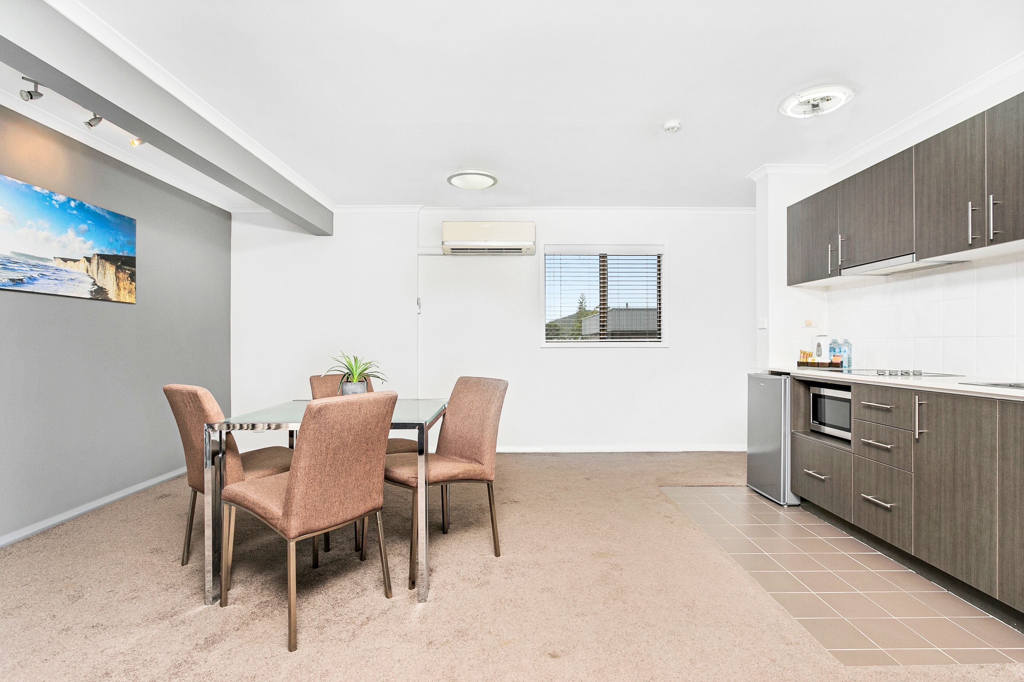 A compact kitchen with grey cabinets, a built-in oven, and a small refrigerator.