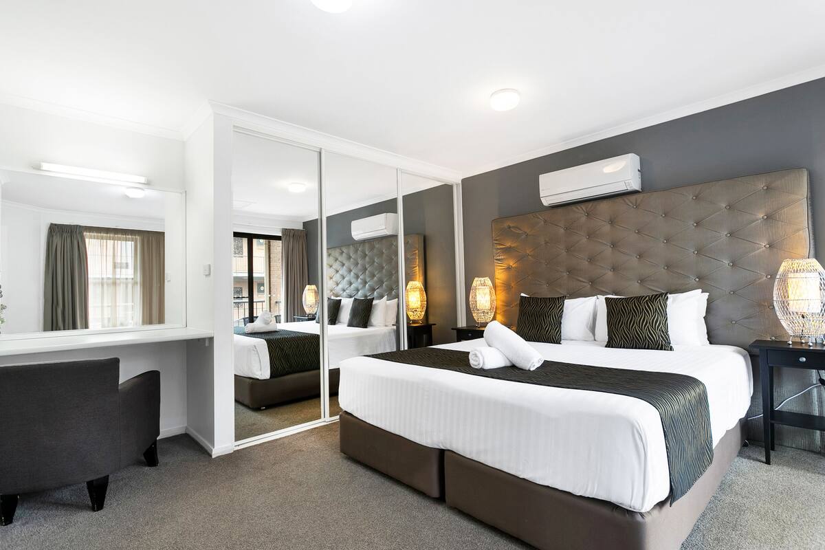 Een moderne hotelkamer met een groot bed, een bureau en een spiegel.