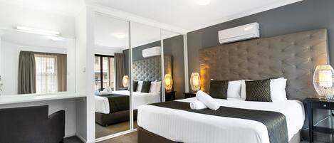 Een moderne hotelkamer met een groot bed, een bureau en een spiegel.