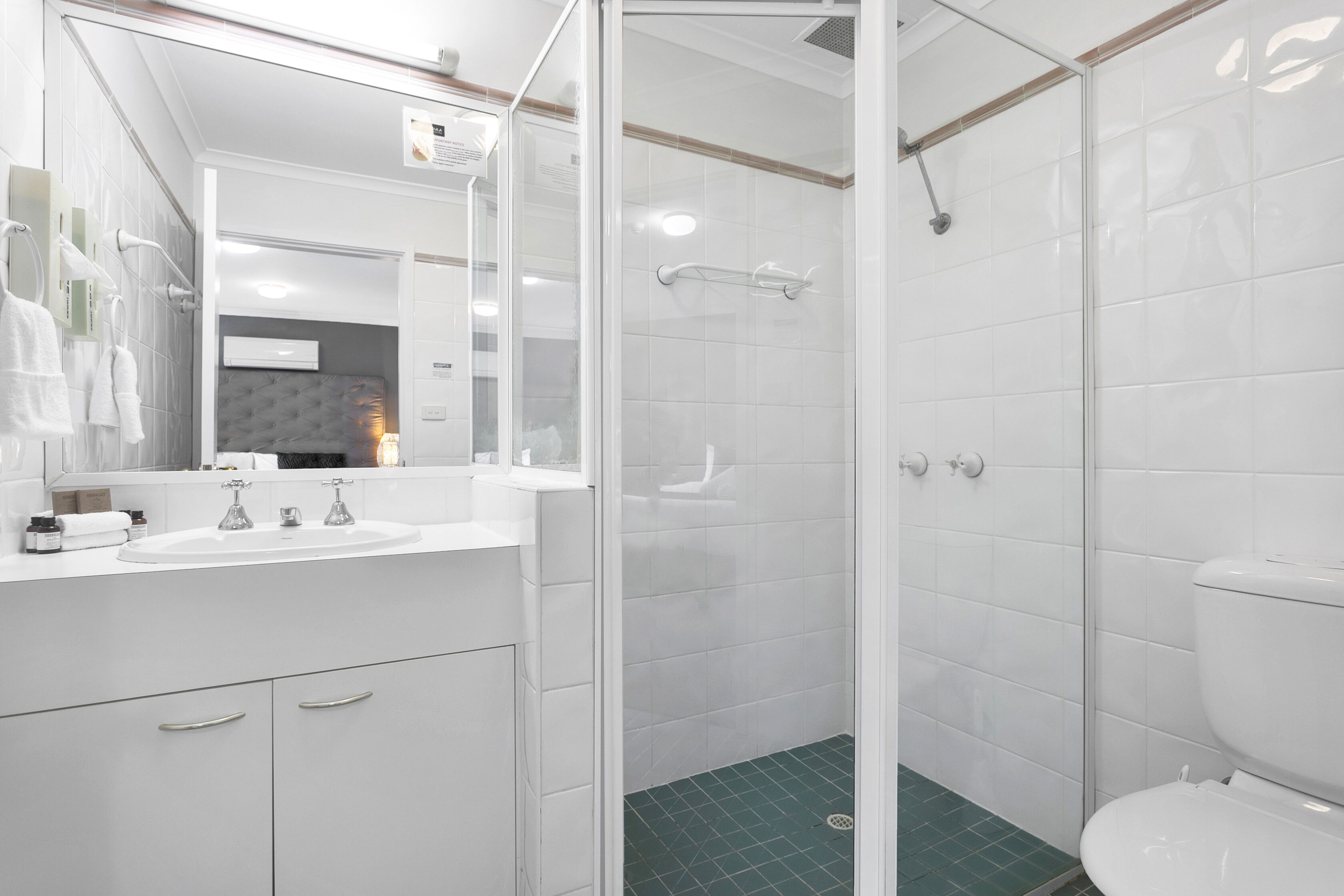 A modern bathroom with a glass shower enclosure, a white sink, and a toilet.