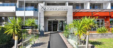 A modern building with a reception area, a sign for a licensed restaurant, and a pathway leading to the entrance.