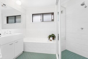 Un baño moderno con tocador blanco, bañera y zona de ducha.