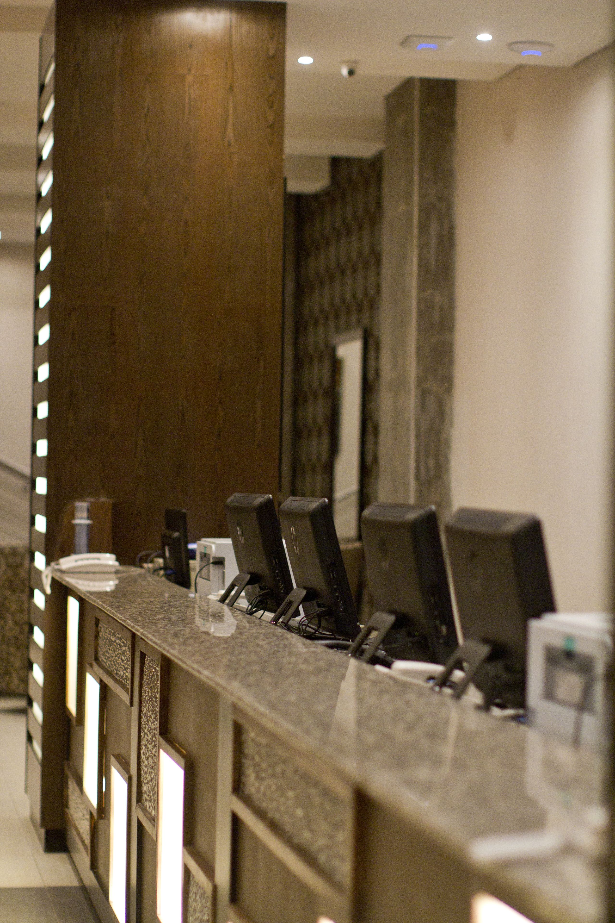A reception desk with multiple computer monitors, a telephone, and a glass display case.