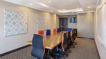 A conference room with a long table, six chairs, and a carpeted floor.