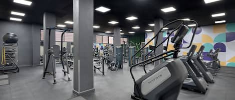 Un gimnasio con cintas de correr, máquinas de pesas y pelotas de ejercicio.