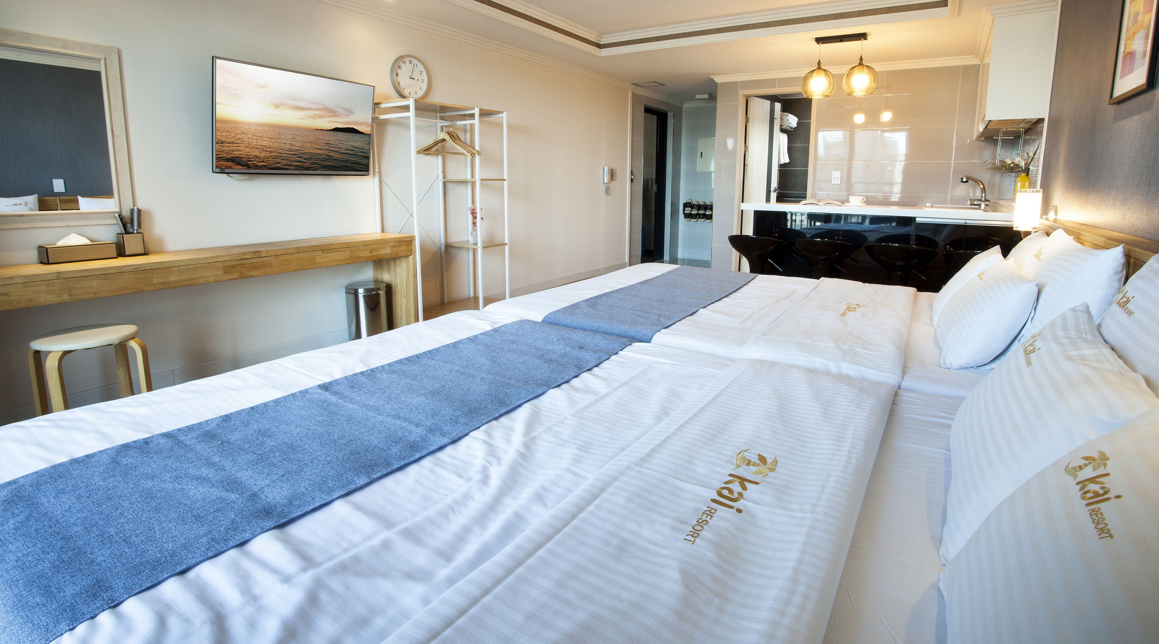 Une chambre d’hôtel avec un grand lit, un bureau avec une chaise, un miroir et une vue sur la mer.