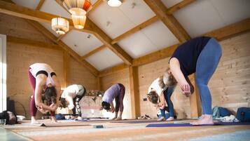 A yoga class in a wooden room with high ceilings and hanging lights.