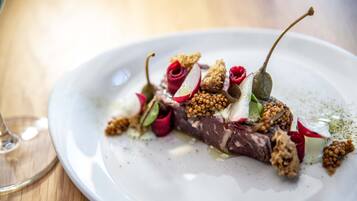 A white plate with a dish of food, a glass of wine, and a wooden table.