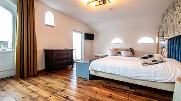 Un dormitorio con una cama grande, un aparador, un escritorio y una ventana con cortinas.