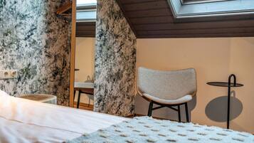 Ein Schlafzimmer mit einem Bett, einem Sessel, einem kleinen Tisch und einem Oberlicht.