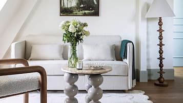 A modern living room with a white sofa, a round table with a vase of flowers, and a tall floor lamp.
