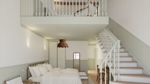 Ein Schlafzimmer mit einem großen Bett, einem Nachttisch aus Holz, einem Stuhl, einem Schreibtisch, einer Pendelleuchte und einer Treppe.