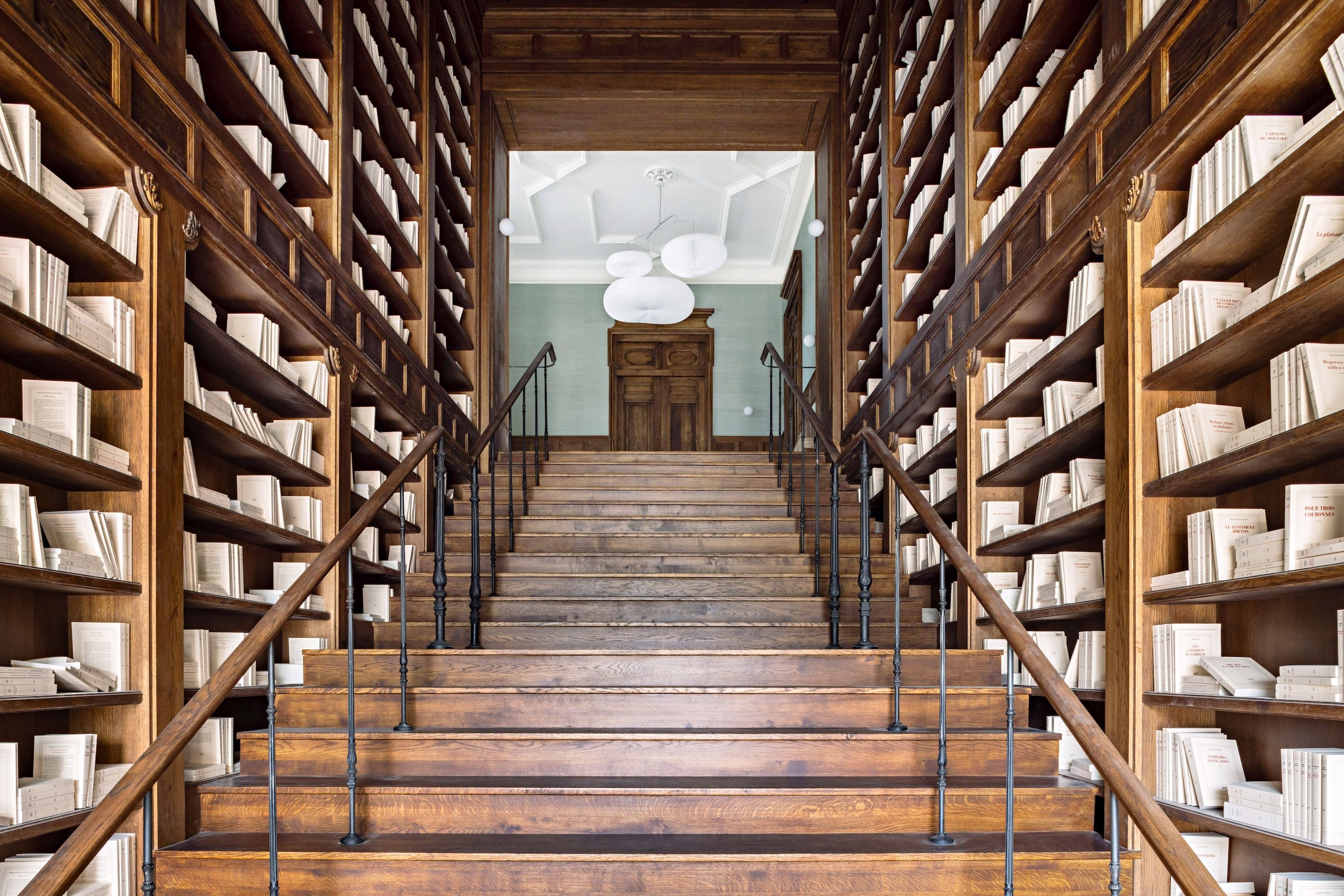 A grand staircase flanked by tall bookshelves in a library setting.