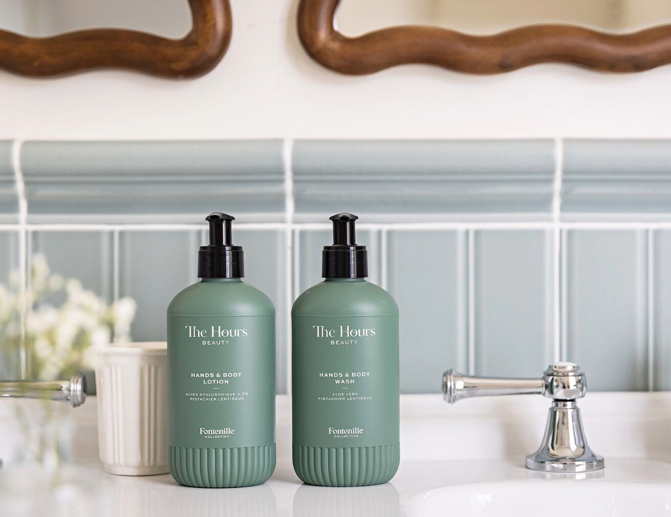 Dos botellas de loción y jabón de The Hours Beauty sobre una encimera de baño.