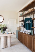 Quarto bem organizado com um armário de madeira exibindo diversos objetos, uma mesa com produtos de cuidados para a pele e uma camisa verde no armário.